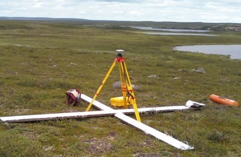 photograph of a satellite ground survey target Figure 1a: This target is effective because it was created on even terrain, away from buildings and trees, it contrasts the ground colour, and the differential GPS unit is in the photo.